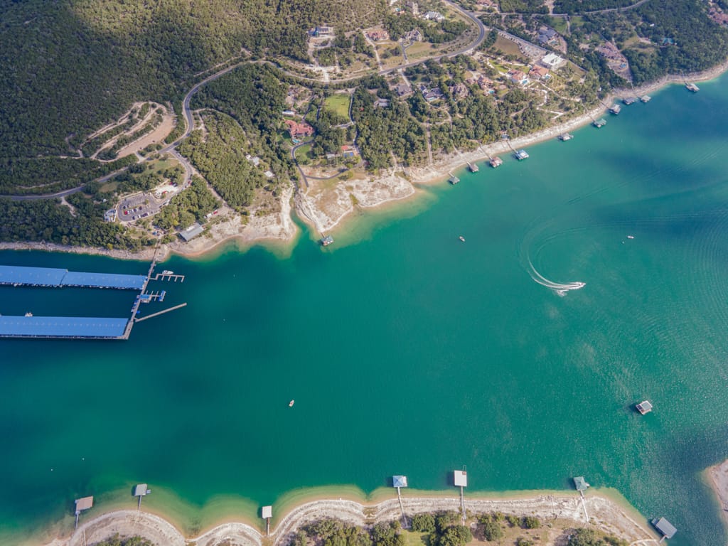 A wooded shoreline along the lake west of Austin on a still morning.