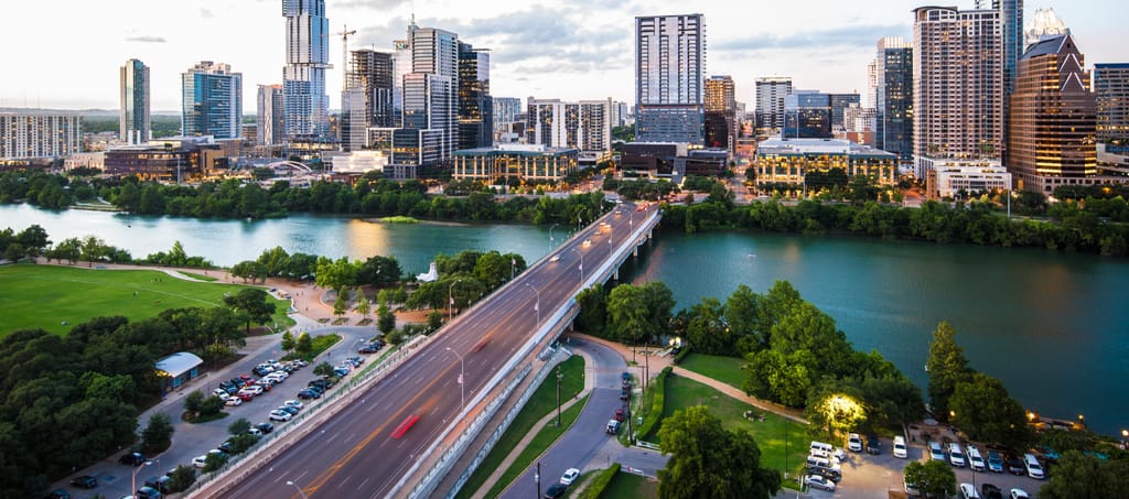 An aerial view across central Austin toward the river and the hills beyond.