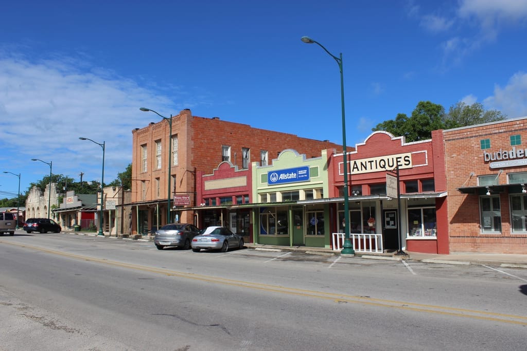 A block of Buda's historic downtown, painted brick storefronts and an antiques shop sign