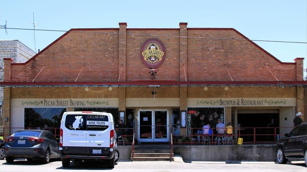 A brick brewery building on the Johnson City square, tables and a van out front