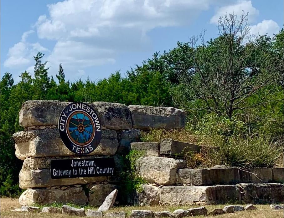 A stone marker in the brush reading City of Jonestown, Gateway to the Hill Country