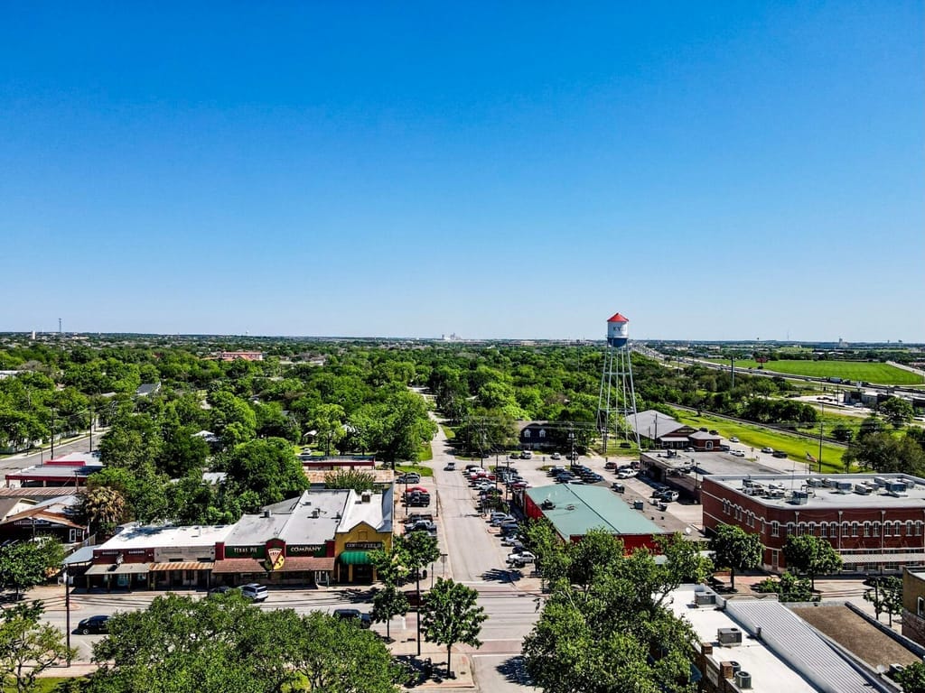Low commercial buildings and a water tower across the flat ground east of Kyle