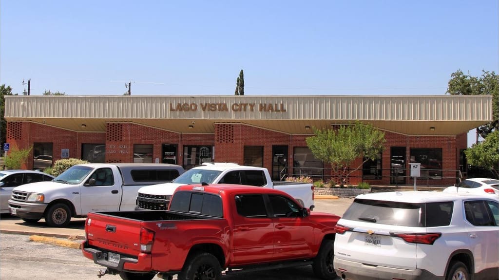 Pickup trucks parked outside the brick Lago Vista city hall