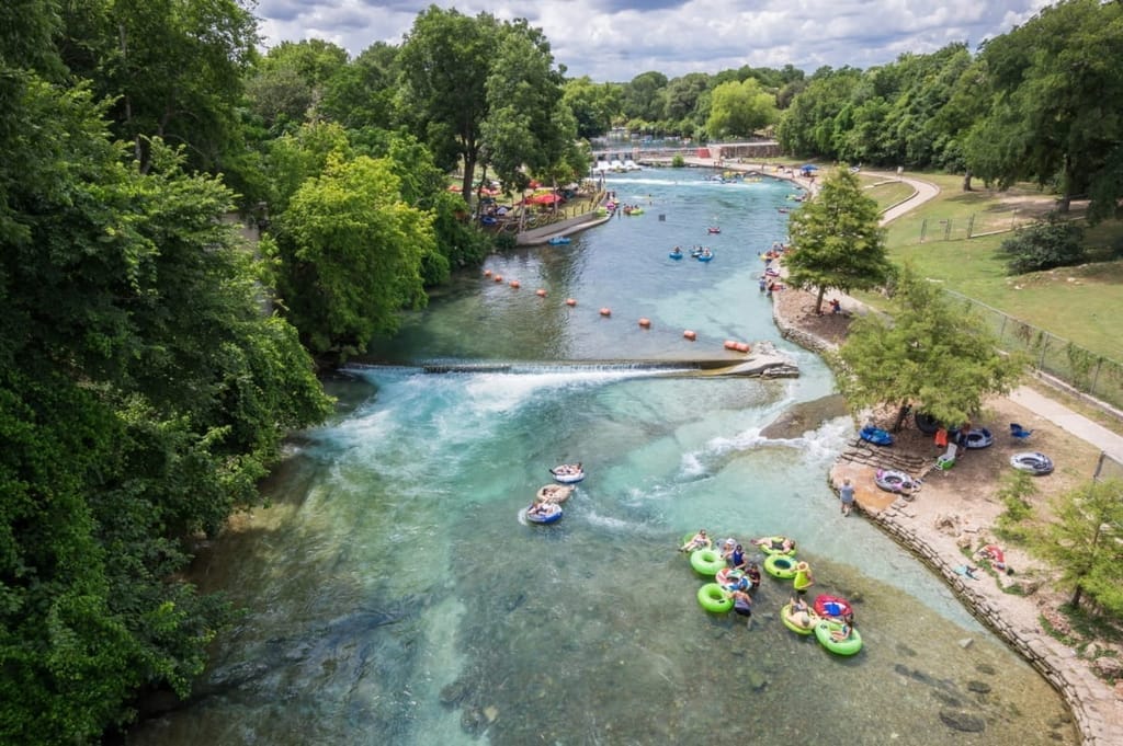 Tubers drifting down a spring-fed New Braunfels river between cypress-lined banks