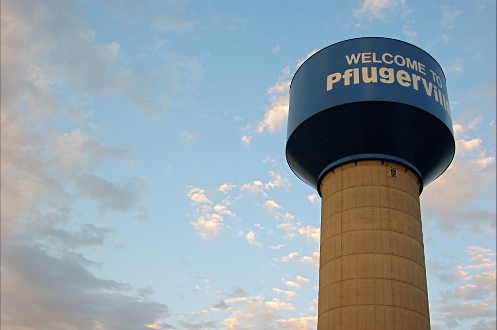 The Pfluger water tower against a blue sky with scattered cloud