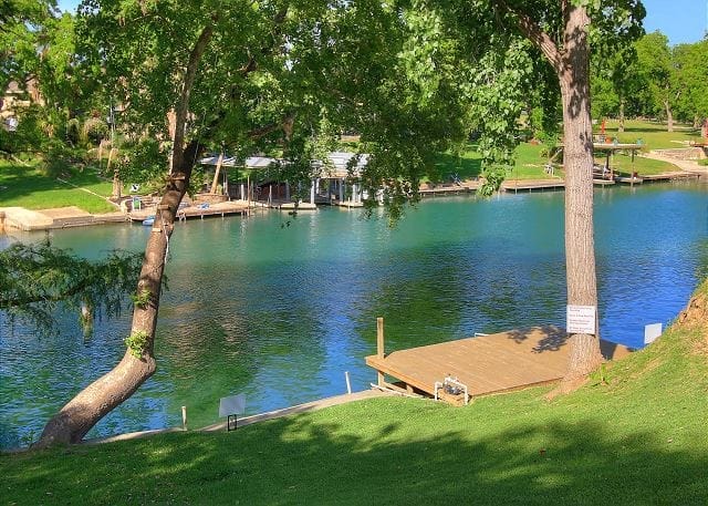 A private wooden dock on a mown bank at Lake Dunlap, boat docks along the far shore