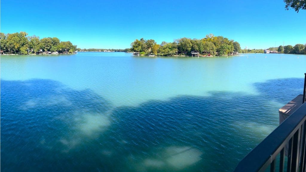 Open water on Lake McQueeney with lakefront houses along the tree-lined far shore
