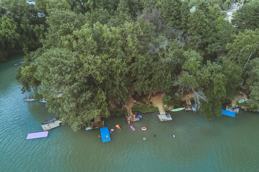 Boat docks and a floating slide on Lake Placid, seen from above through heavy tree cover