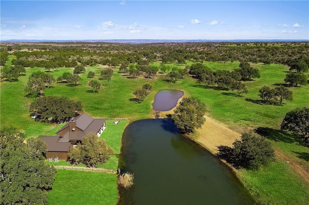 Hill Country ranchland under a wide sky, a stock pond and a ranch house among scattered oak motts