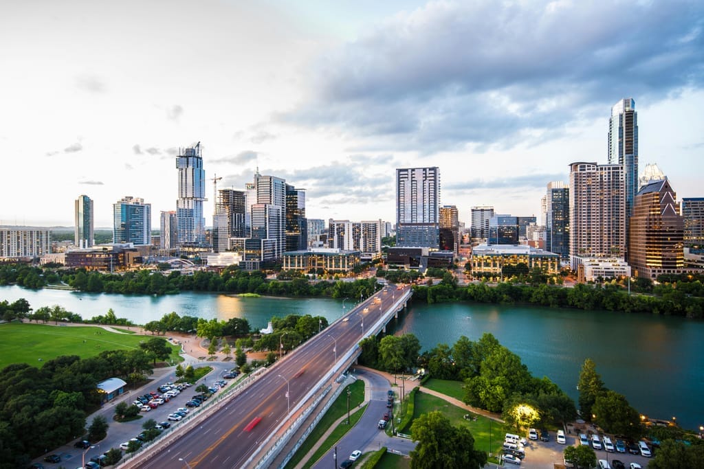 The downtown Austin skyline across Lady Bird Lake, traffic crossing the Congress Avenue bridge below