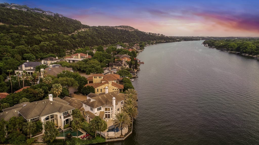 Lake Austin from the air, houses stepping down a wooded bluff to the water on the near shore